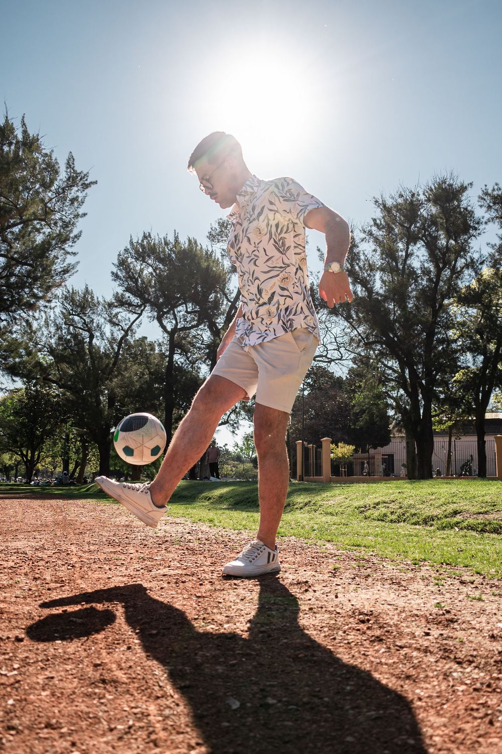 Man juggling a soccer ball in a sunny park