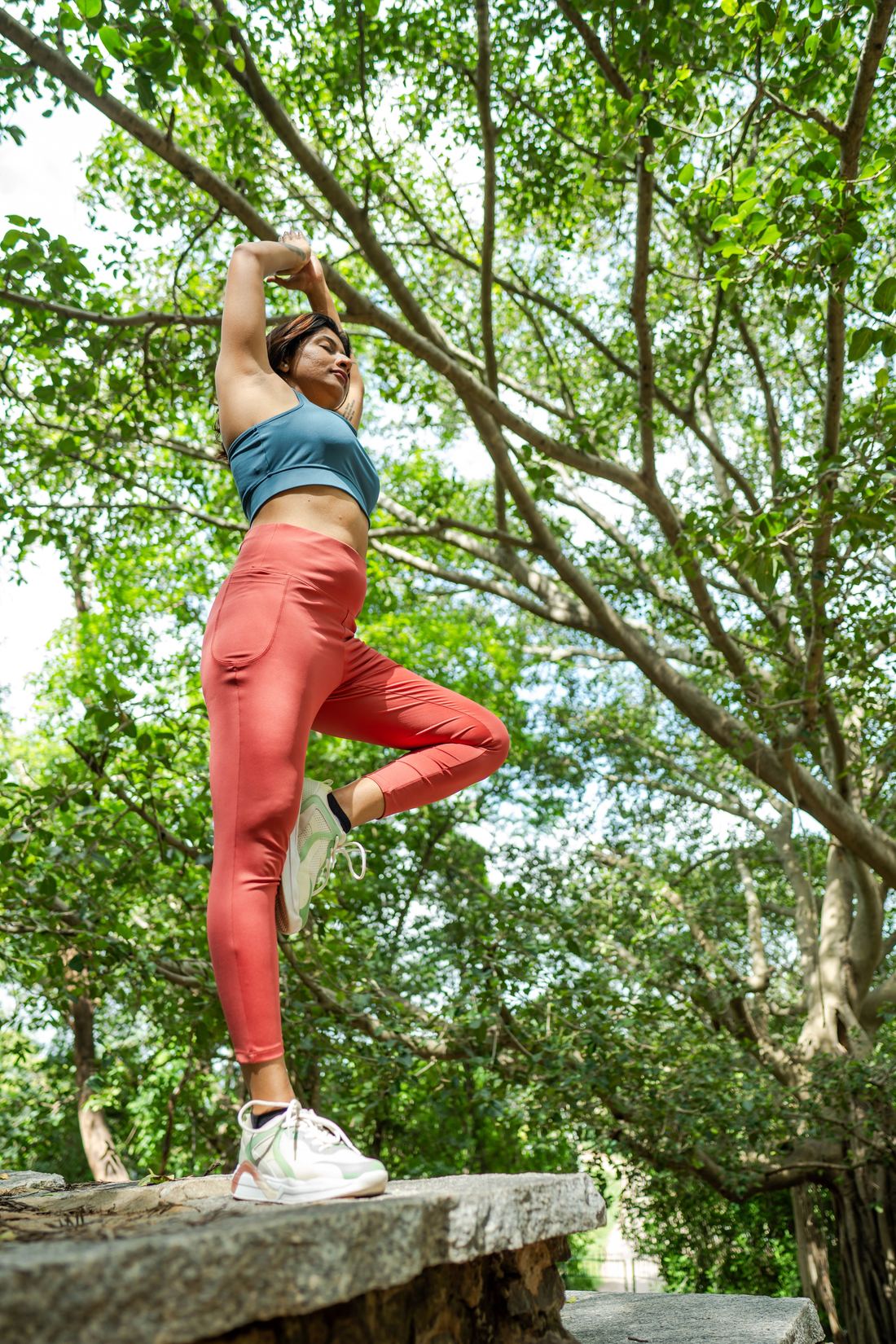 Woman stretching outdoors beneath trees